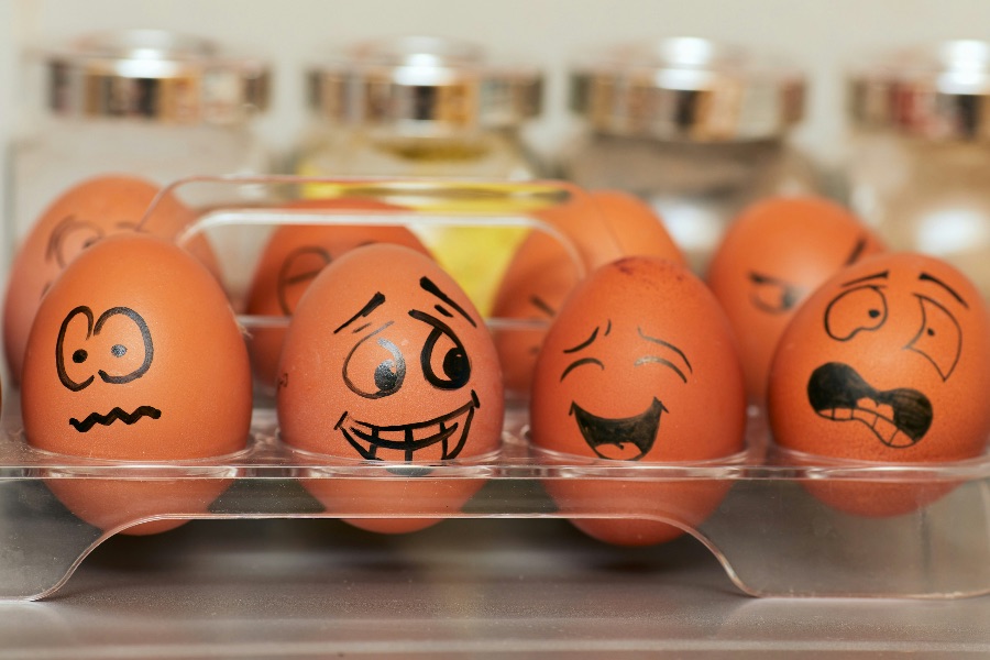 A carton of eggs, each egg with a face representing a different human emotion inscribed on its surface